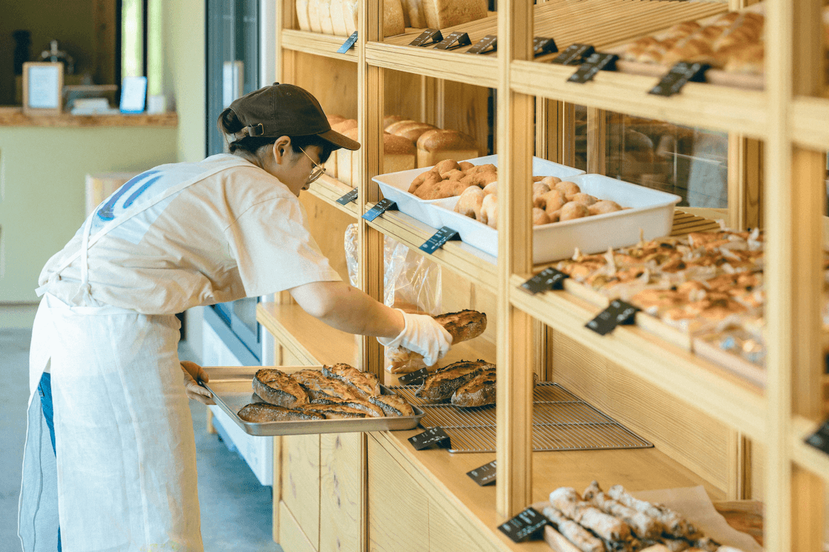 腰をかがめてパンを店頭に並べているところ